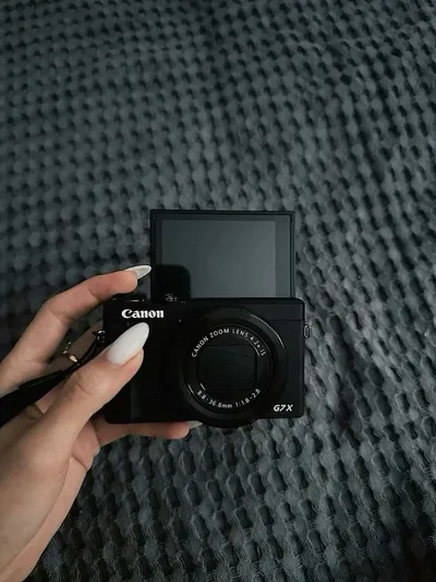 Hand holding a Canon G7X compact camera