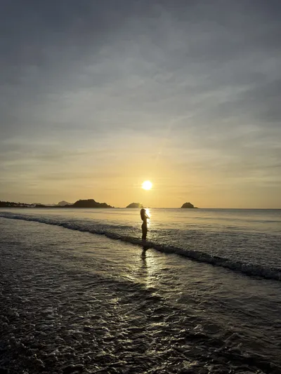 Person standing in the sea at sunset