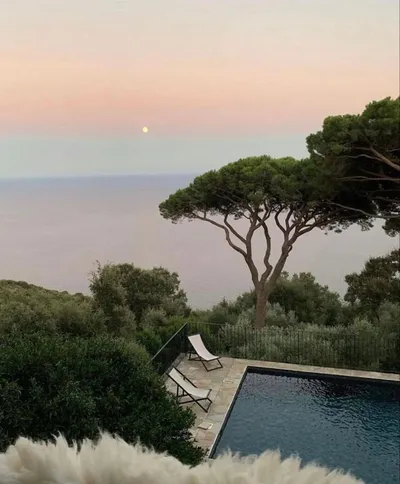 Pool among pine trees overlooking the sea at sunset