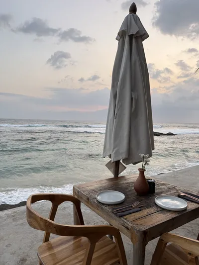 Closed parasol and dining table on a beach at dusk