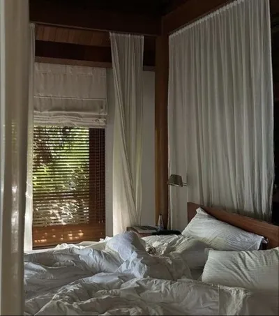 Unmade bed in a room with white curtains